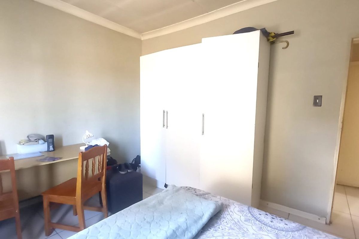 A bedroom featuring tiled flooring, a built-in wardrobe, and coved ceiling details. The room requires minor maintenance to the ceiling panels.