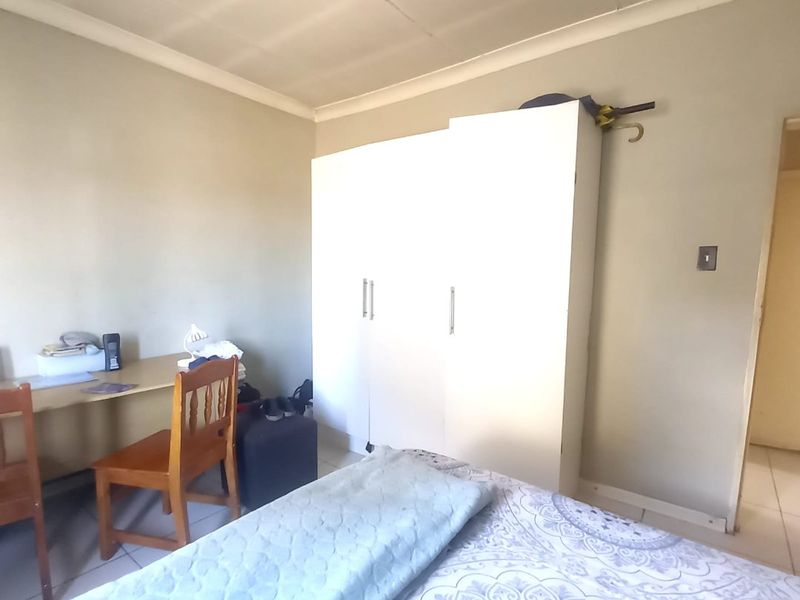 A bedroom featuring tiled flooring, a built-in wardrobe, and coved ceiling details. The room requires minor maintenance to the ceiling panels.