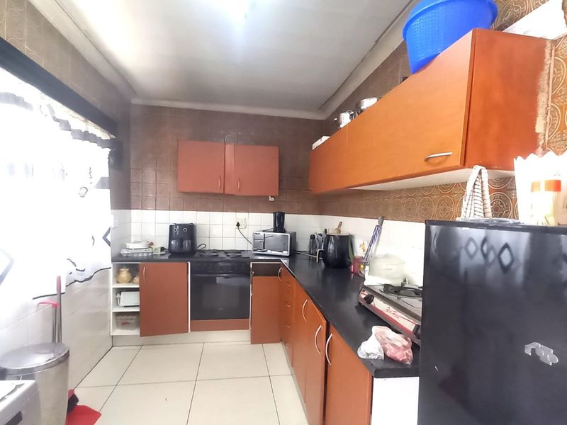 A functional kitchen featuring built-in cabinetry, laminate countertops, and a built-in oven with a tiled backsplash and flooring.