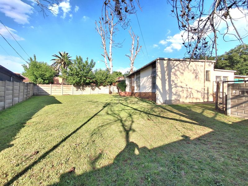 Spacious rear garden featuring a large lawn area, enclosed by precast concrete boundary walls and including a side access gate.