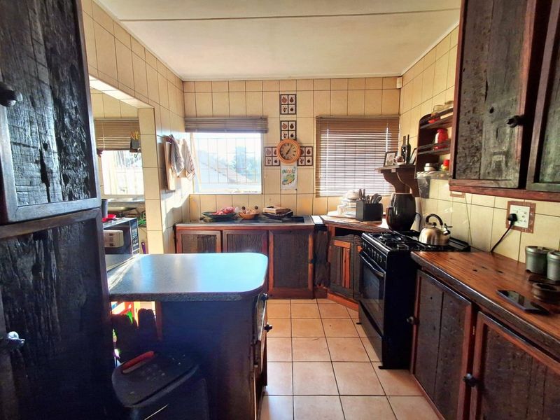 A functional kitchen featuring rustic wooden cabinetry, tiled splashbacks, and a gas stove, offering a traditional layout with ample counter space.