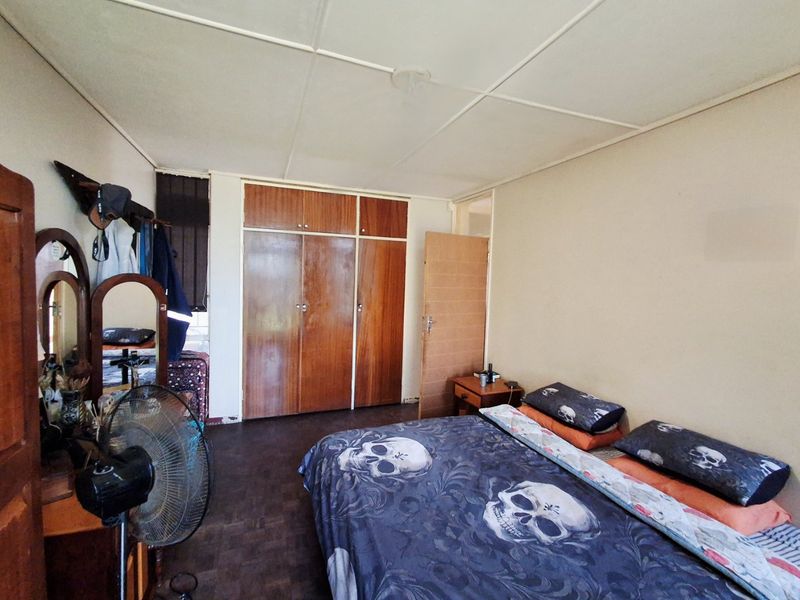 A bedroom featuring built-in wooden cupboards and a tiled ceiling, offering a functional space with potential for modernization.
