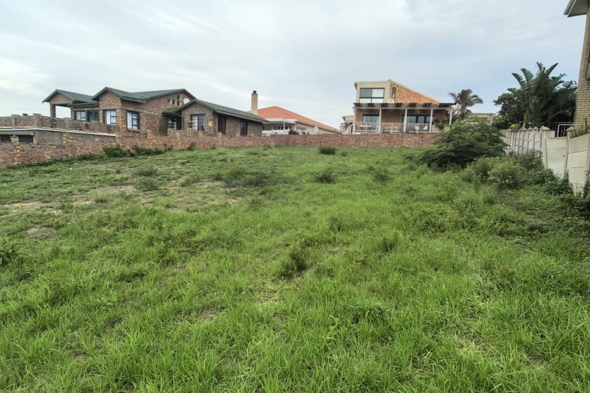 A vacant residential plot featuring natural grass coverage and established boundary walls, situated in a developed neighborhood.