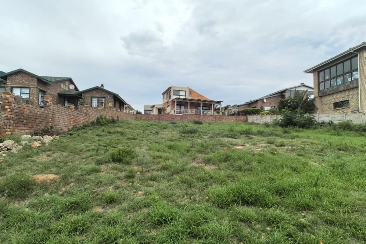 A vacant residential plot featuring a gentle slope, enclosed by brick and precast concrete boundary walls in an established neighborhood.