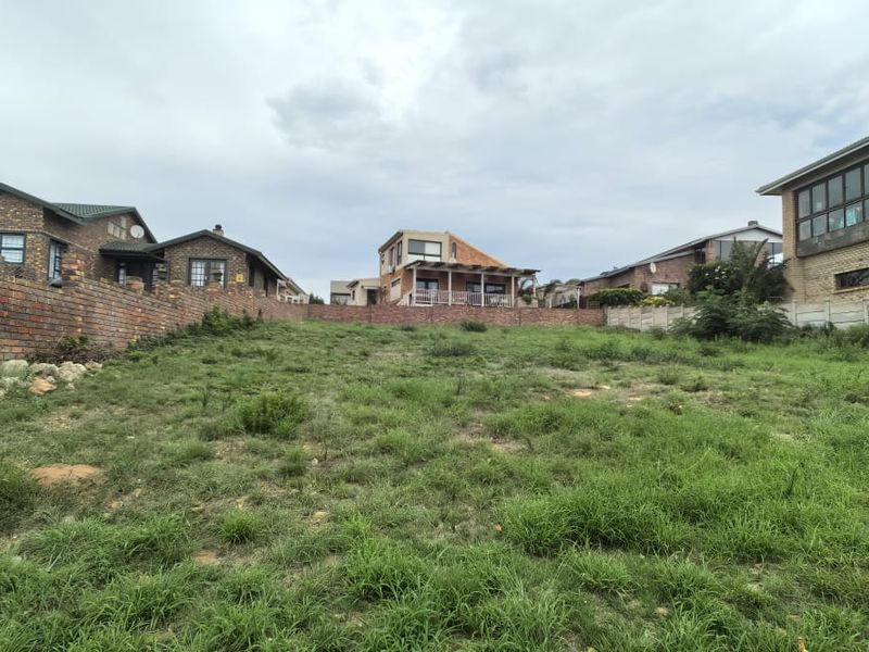 A vacant residential plot featuring a gentle slope, enclosed by brick and precast concrete boundary walls in an established neighborhood.