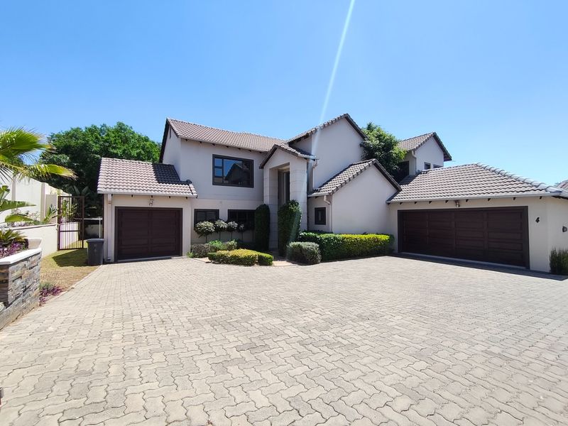 A well-maintained double-story residential property featuring a paved driveway, double garage, and neat landscaped garden.