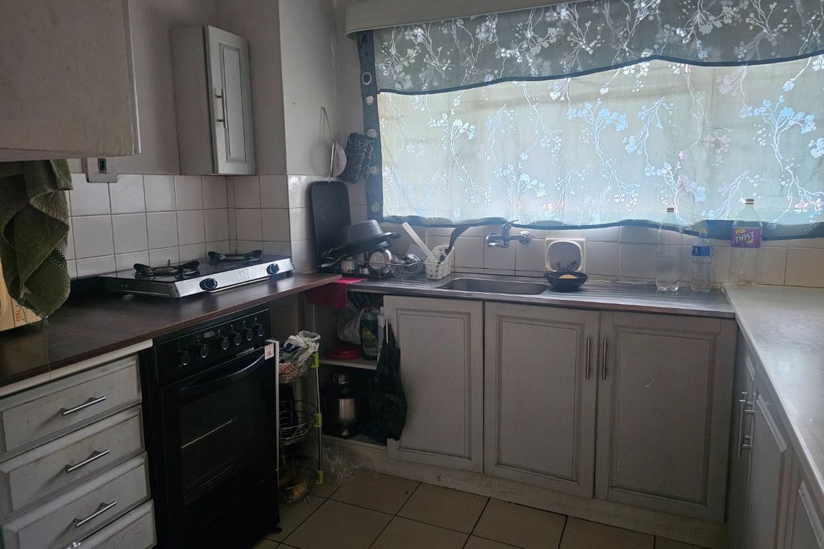 A functional kitchen featuring built-in cabinetry, a stainless steel sink, tiled backsplash, and a gas hob with an integrated oven.
