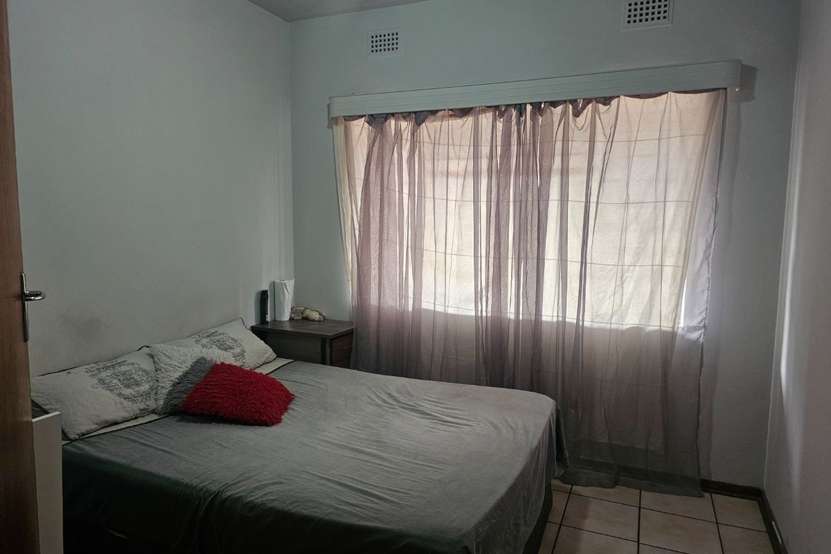 A standard bedroom featuring tiled flooring and wall-mounted ventilation grilles, providing a functional and neutral living space.