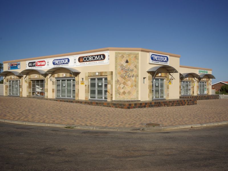 Front exterior view of Protea Park commercial building featuring paved parking, security gates, and prominent signage.