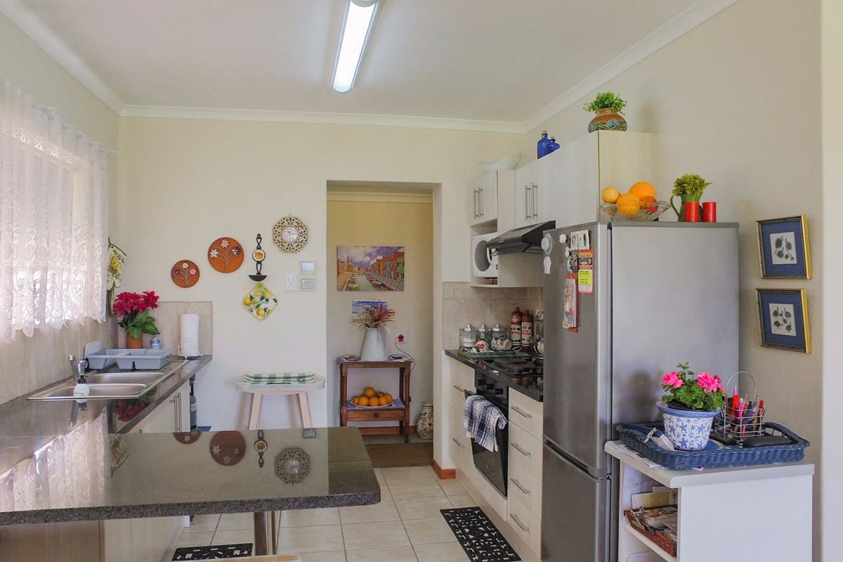 Functional kitchen featuring granite countertops, built-in oven, hob, extractor fan, and double sink with tiled flooring and ample cabinetry.