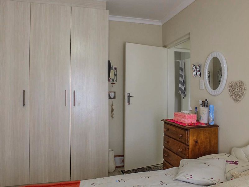 A bedroom featuring light-toned built-in cupboards and neutral wall finishes, providing a functional and tidy sleeping space.