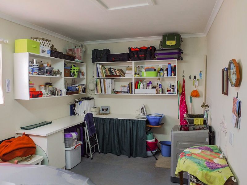 A functional laundry area featuring built-in wall shelving and a utility sink, providing practical storage and workspace for household tasks.