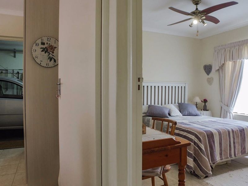 A bedroom featuring a ceiling fan and built-in storage, with an adjacent view into a garage space.