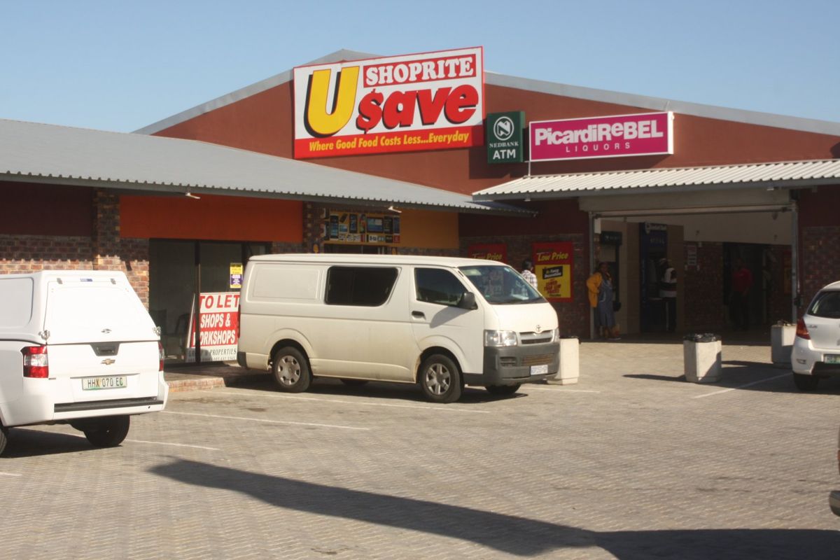 Front exterior view of a commercial retail center featuring paved parking, covered walkways, and prominent storefront signage.