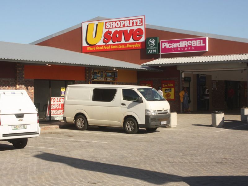 Front exterior view of a commercial retail center featuring paved parking, covered walkways, and prominent storefront signage.