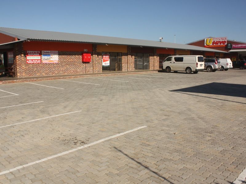 Front exterior view of a commercial retail center featuring a paved parking lot, brick facade, and prominent signage for anchor tenants.