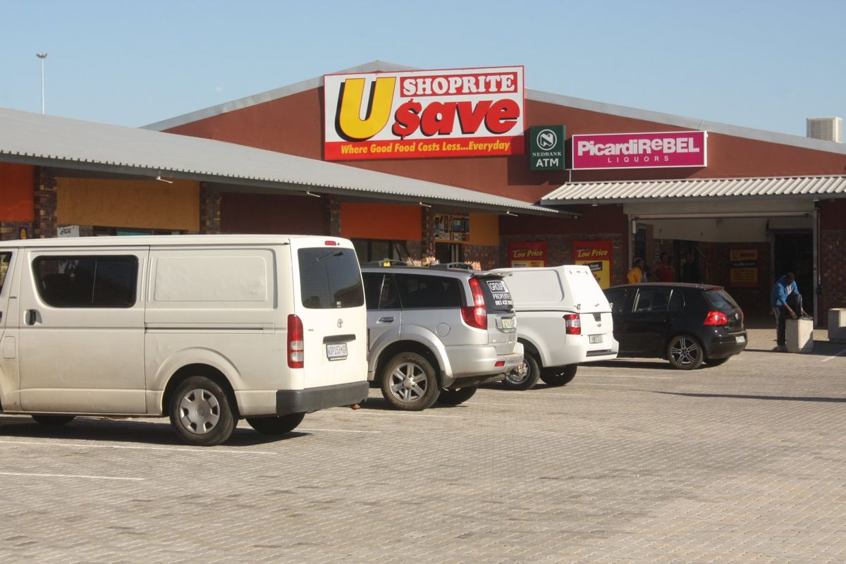 Front exterior view of a commercial retail center featuring a paved parking area, brick facade, and prominent signage for Usave and PicardiRebel.