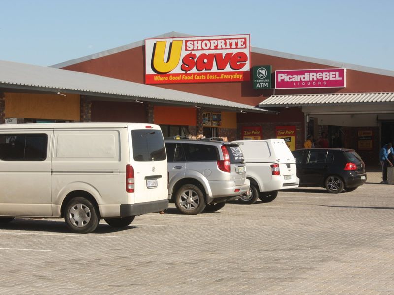 Front exterior view of a commercial retail center featuring a paved parking area, brick facade, and prominent signage for Usave and PicardiRebel.