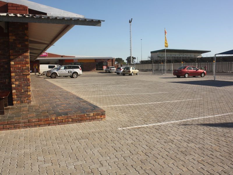 Commercial property exterior featuring a paved parking lot, brick facade building, and covered walkway area.