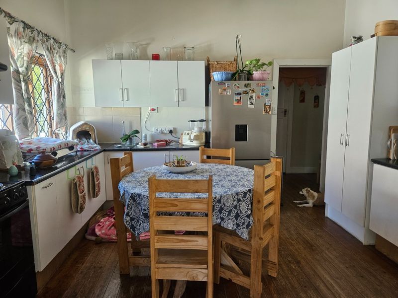 A functional kitchen featuring white cabinetry, dark countertops, and timber flooring, providing a practical space for cooking and casual dining.
