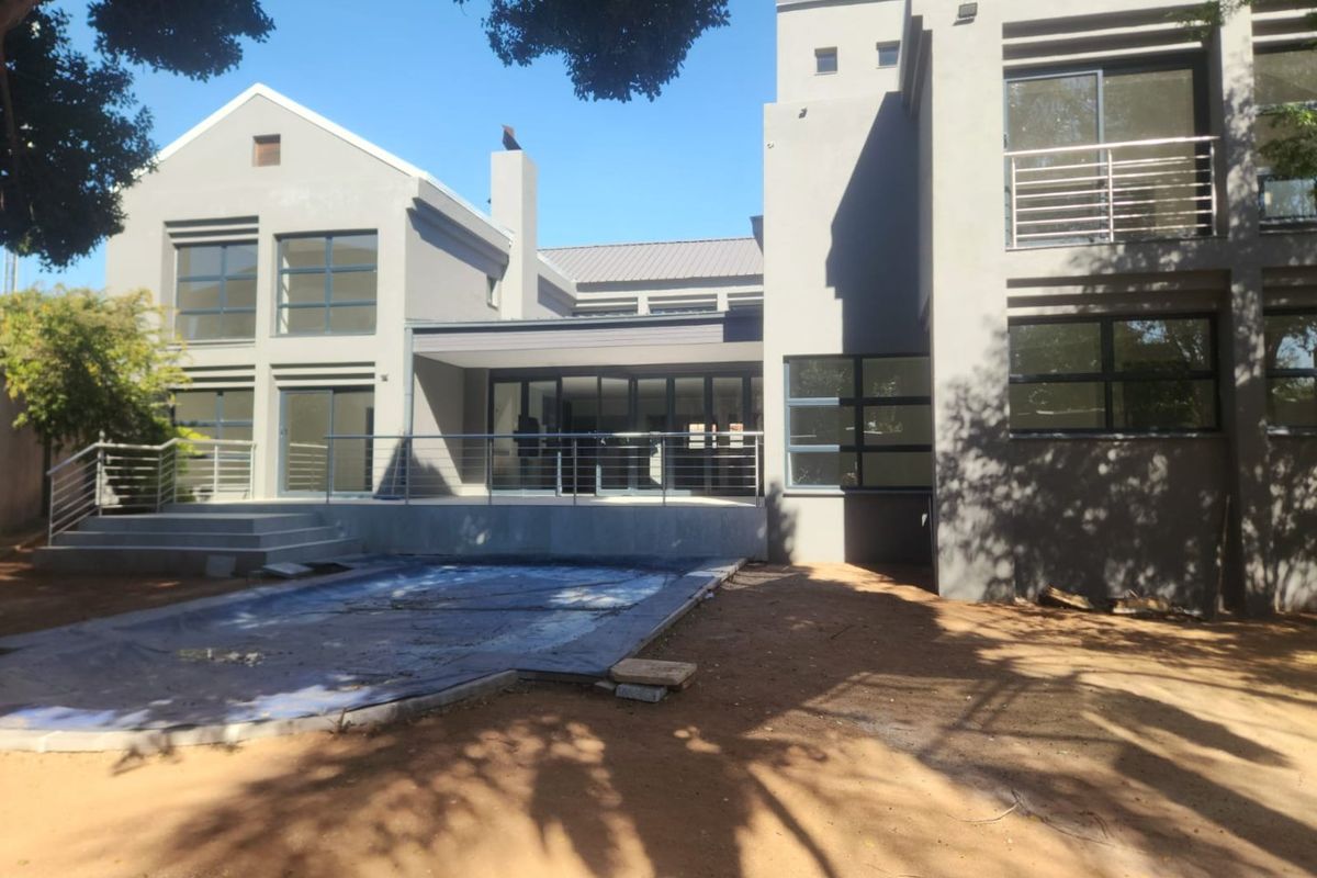 Rear view of a modern multi-story house featuring a swimming pool, covered patio, balcony, and large glass sliding doors.