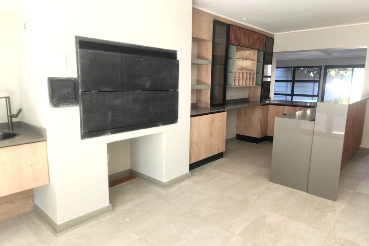 Modern kitchen featuring custom cabinetry, stone countertops, integrated shelving, and a built-in braai, offering a clean and functional space.