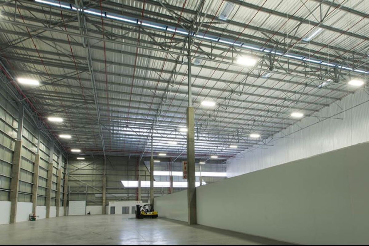 Spacious industrial warehouse featuring high ceilings with exposed steel trusses, polished concrete flooring, and high-bay lighting, suitable for logistics or manufacturing operations.