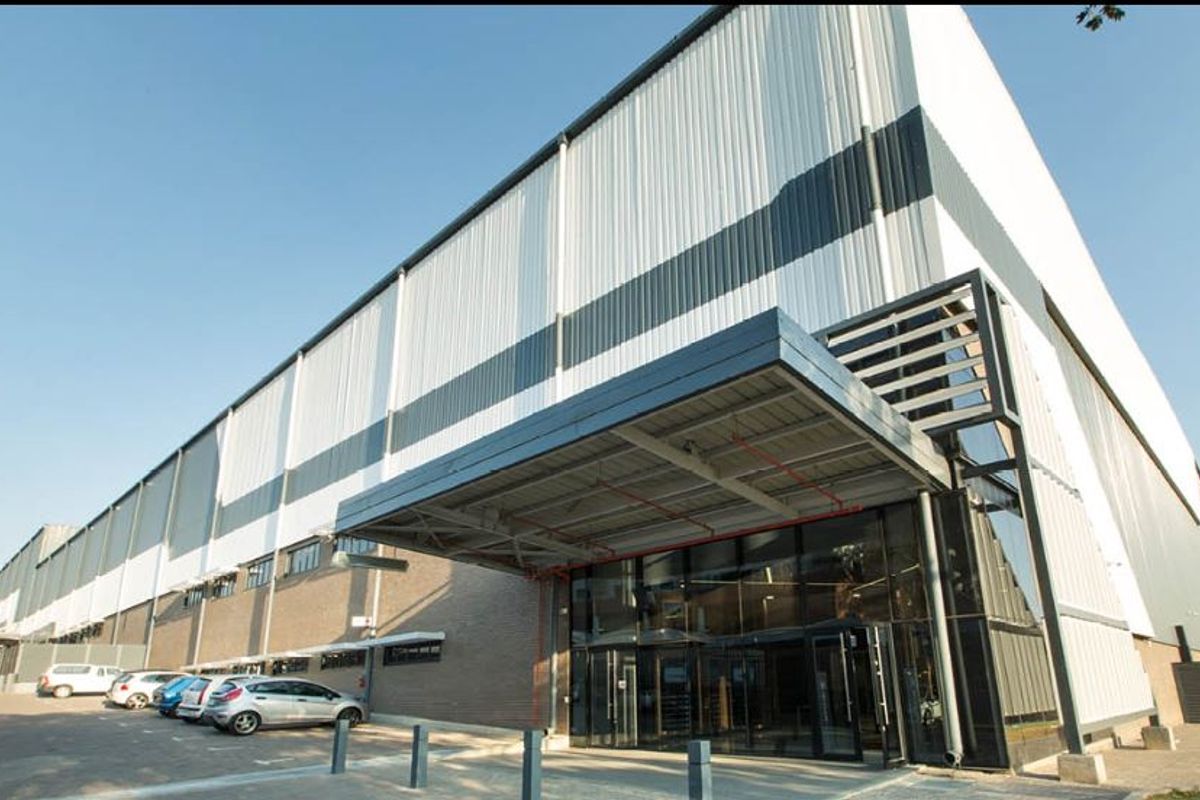 Modern industrial facility featuring a prominent glass entrance, metal cladding, and a covered canopy, providing a professional and well-maintained exterior appearance.