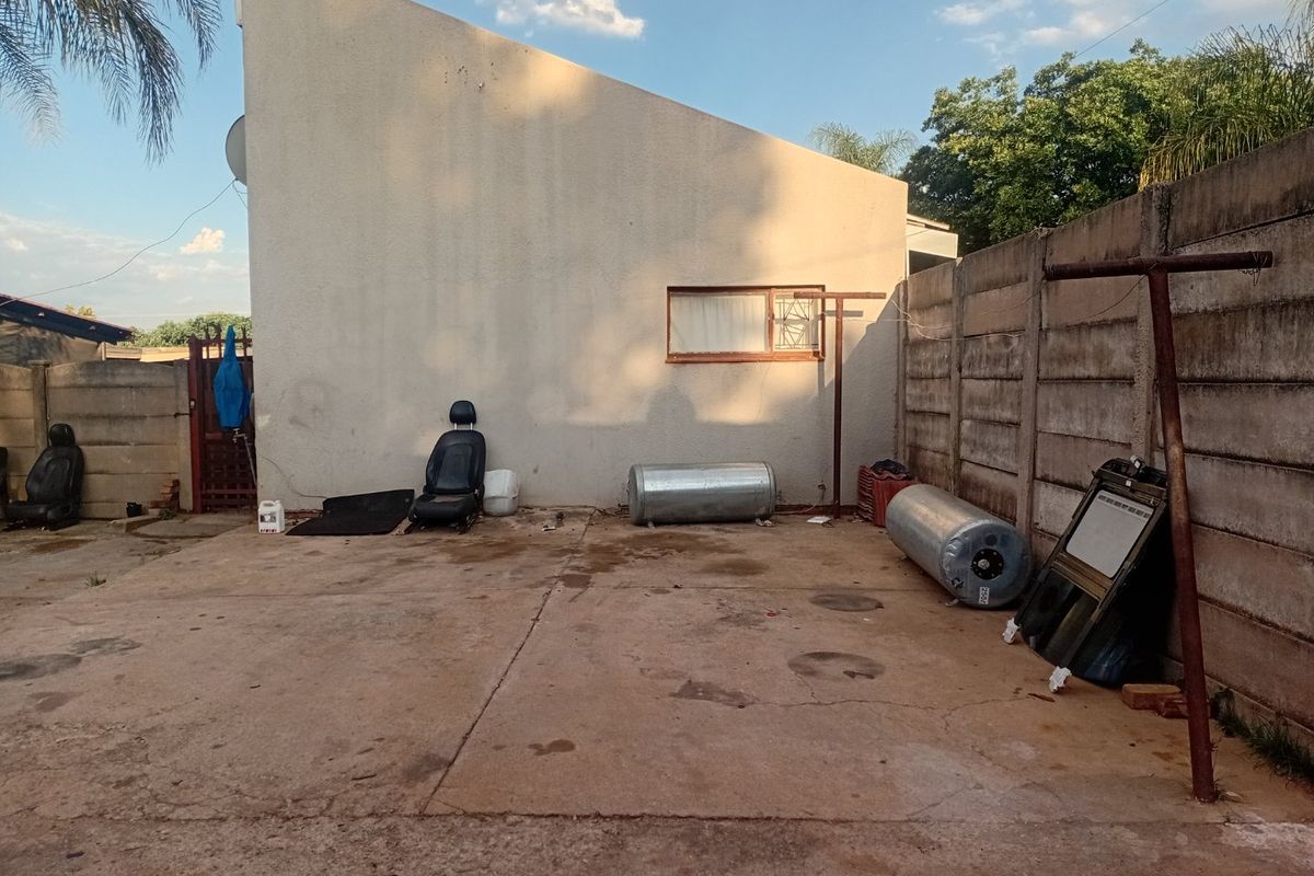 Rear exterior area featuring a concrete paved yard, boundary wall, and metal washing line, requiring maintenance and clearing of debris.