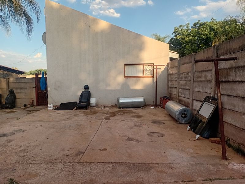Rear exterior area featuring a concrete paved yard, boundary wall, and metal washing line, requiring maintenance and clearing of debris.