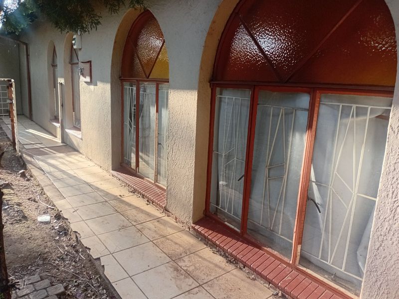 Rear exterior view of the townhouse featuring arched windows with security bars and a tiled walkway along the building perimeter.