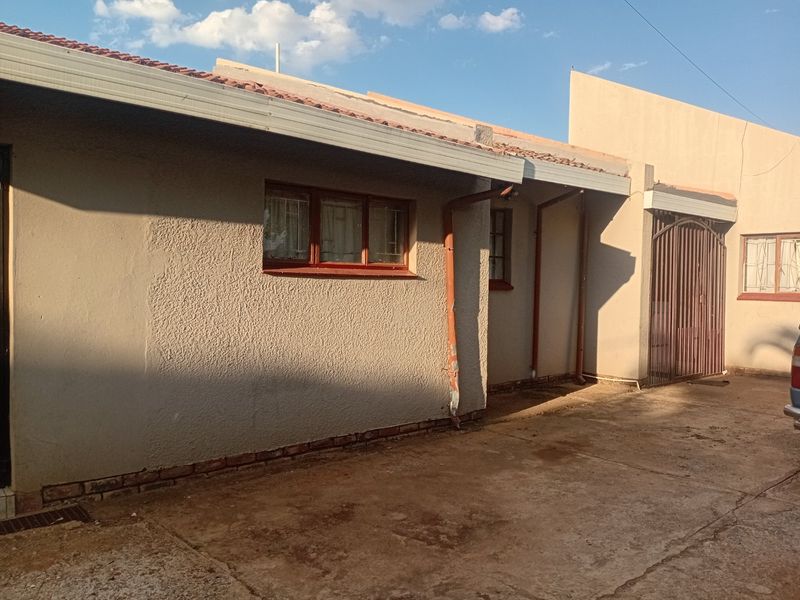 Front exterior view of the townhouse featuring a concrete driveway, tiled roof, and metal security gate access.