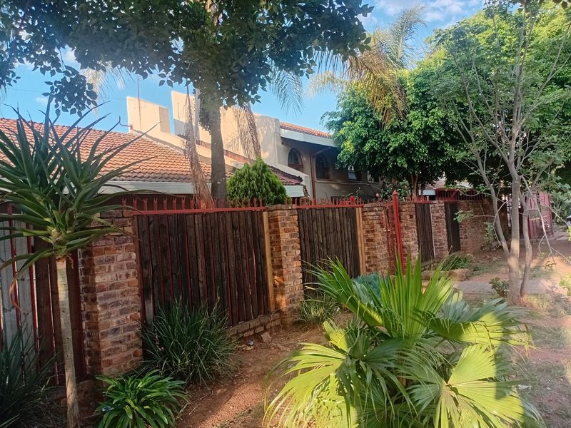 Front exterior view of the townhouse featuring a brick and timber boundary wall with security spikes and established garden landscaping.