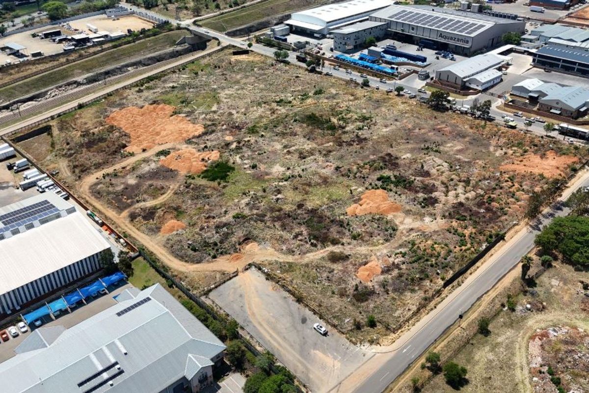 Aerial view of a large, undeveloped vacant residential land parcel situated in an industrial and commercial area.
