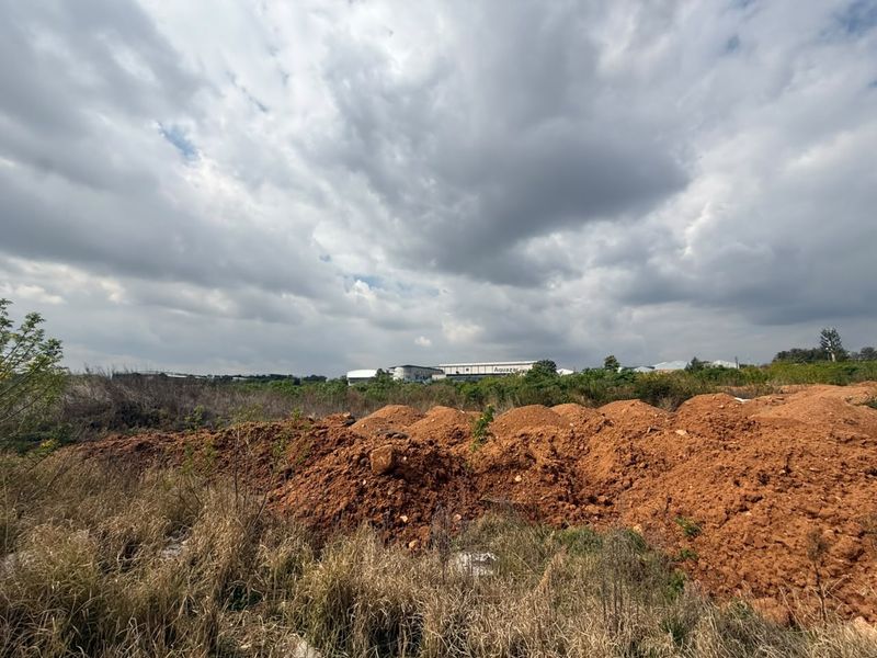 A view of an undeveloped residential plot featuring uneven terrain and earth mounds, suitable for future construction projects.