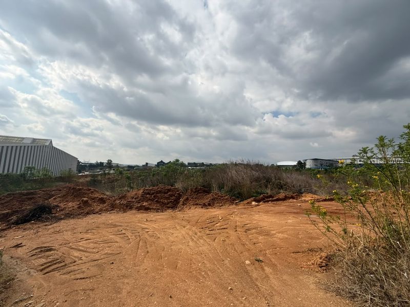 A vacant residential plot featuring cleared earth and natural vegetation, ready for development in a suburban setting.