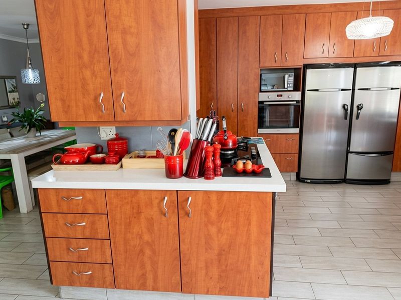 A well-maintained kitchen featuring warm-toned wooden cabinetry, stone countertops, and integrated appliances, offering a functional and classic layout.