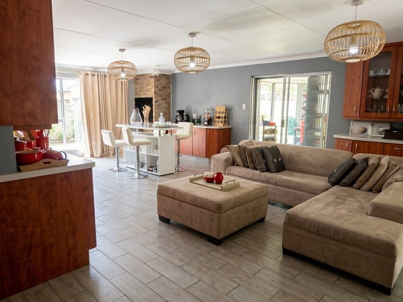 Spacious open-plan living area featuring tiled flooring, built-in cabinetry, a brick fireplace, and sliding glass doors leading to the outdoor space.