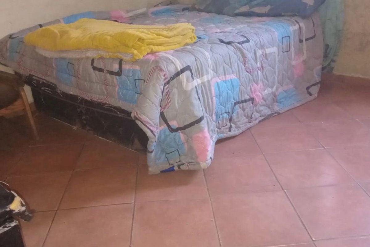 A bedroom featuring tiled flooring and plain wall finishes, requiring cosmetic updates to improve the overall aesthetic and condition of the space.