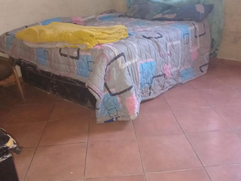 A bedroom featuring tiled flooring and plain wall finishes, requiring cosmetic updates to improve the overall aesthetic and condition of the space.