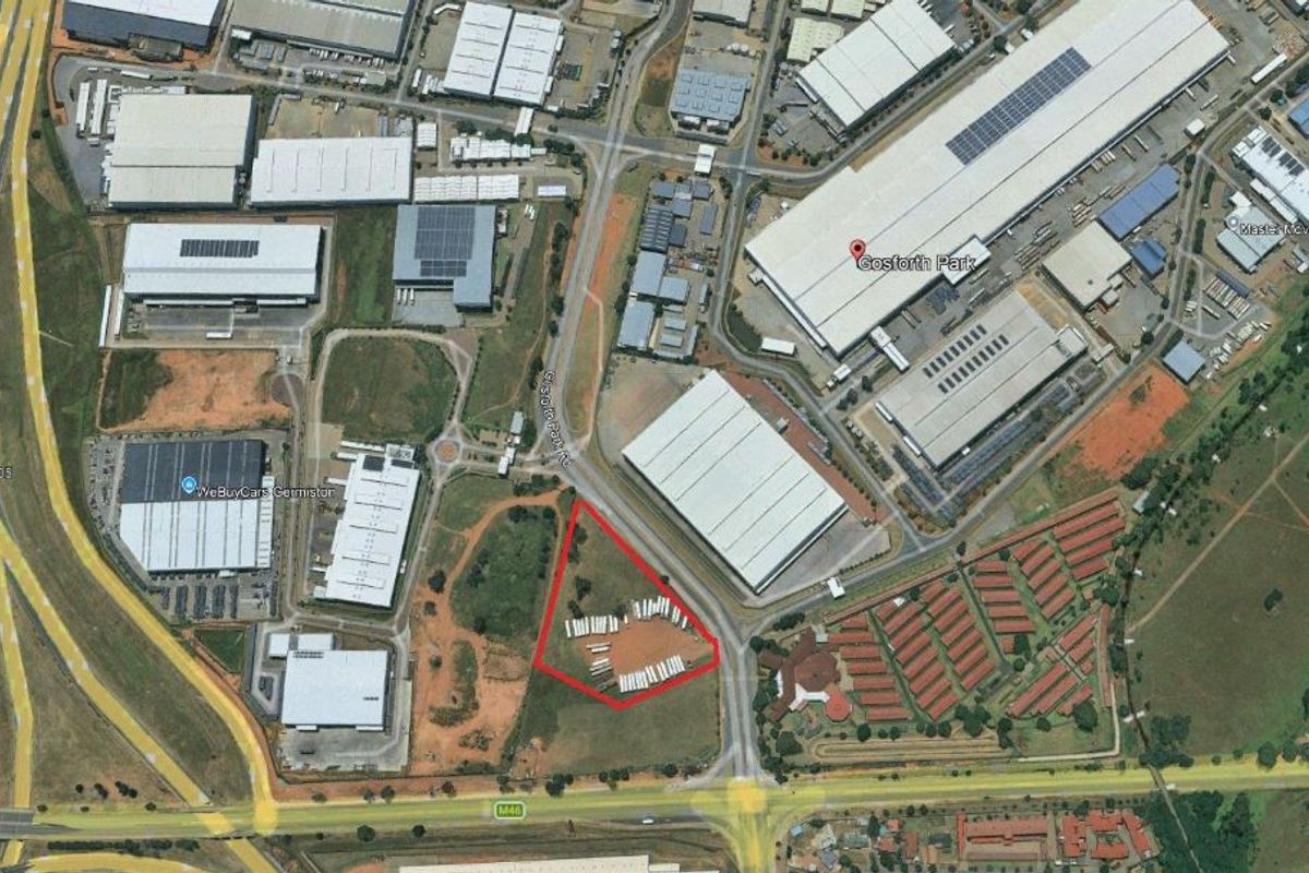 Aerial view of a vacant residential land plot situated in a developed industrial and commercial area with convenient road access.