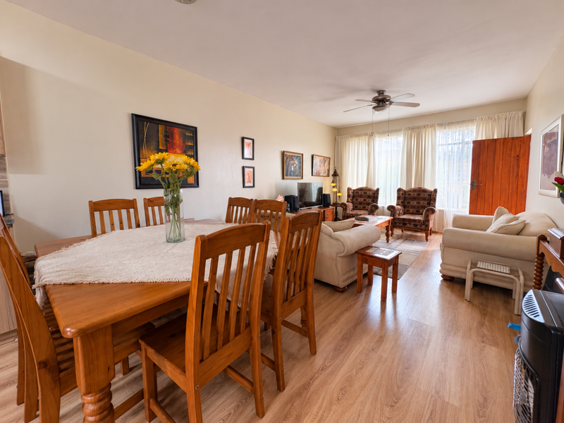 Spacious open-plan living and dining area featuring light laminate flooring and a ceiling fan, offering a functional layout for comfortable daily living.