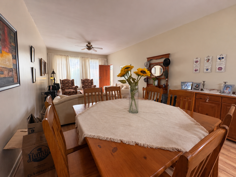 An open-plan living and dining area featuring laminate flooring and a ceiling fan, offering a functional layout for daily living and entertaining.