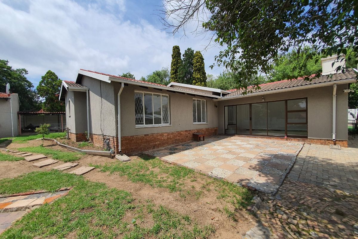 Rear view of the house featuring a paved patio area, sliding glass doors, and a garden with a stepped stone pathway.