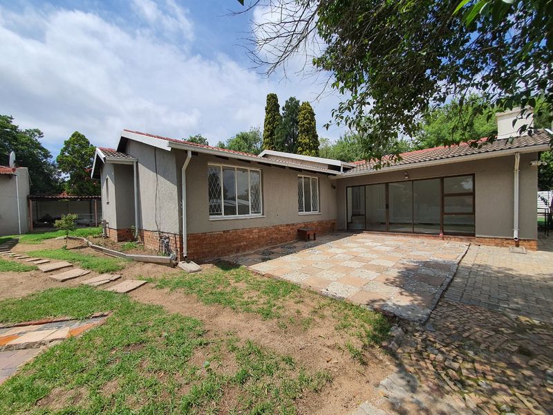 Rear view of the house featuring a paved patio area, sliding glass doors, and a garden with a stepped stone pathway.