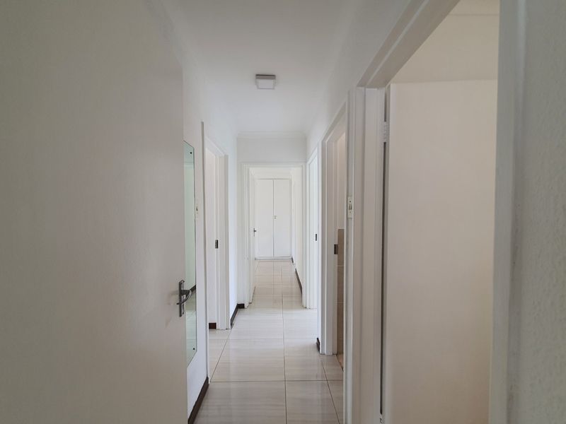 A clean and bright interior hallway featuring neutral tiled flooring and multiple internal doorways leading to various rooms.