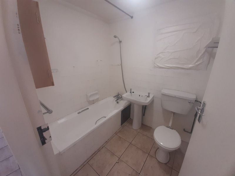 A dated bathroom featuring a standard bathtub, pedestal basin, and toilet, requiring significant cosmetic updates and renovation to improve its condition and appeal.