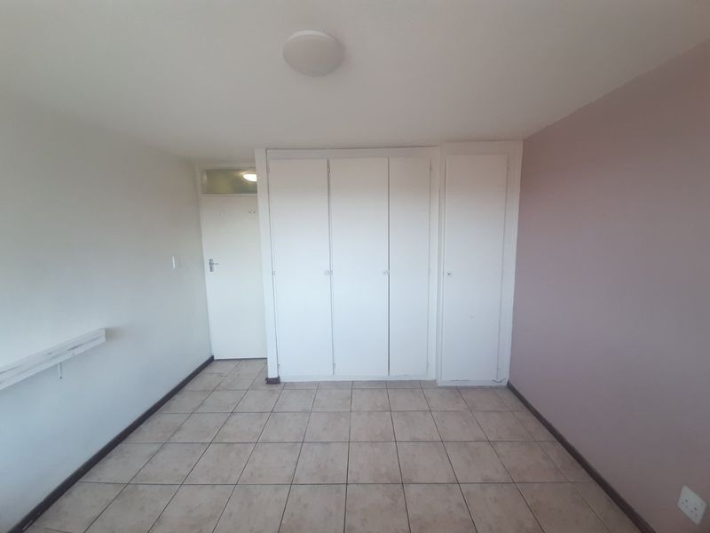 An empty bedroom featuring tiled flooring and built-in cupboards, providing a blank canvas for personalization and interior design updates.