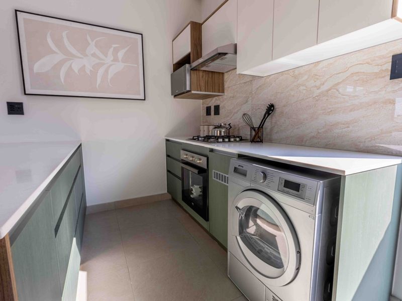 Modern, compact scullery featuring sleek cabinetry, stone countertops, integrated oven, gas hob, and high-quality finishes, providing an efficient and stylish workspace.