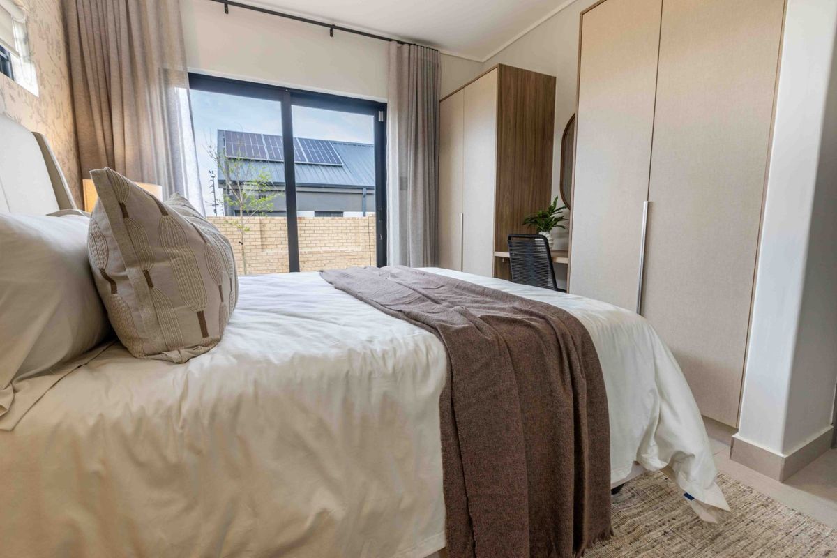 A well-appointed bedroom featuring modern built-in cupboards and a sliding glass door that provides access to the exterior.